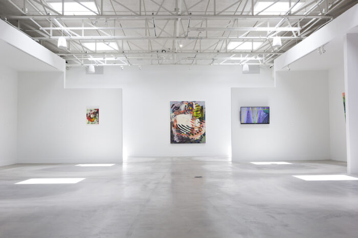 paintings and a tv hanging in a gallery space